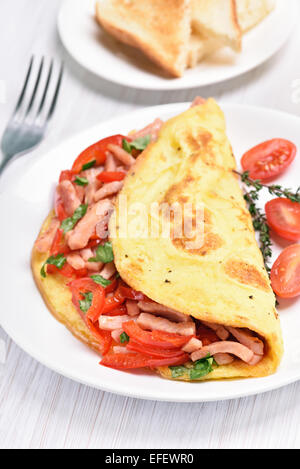 Scrambled eggs with bacon and vegetables on white plate Stock Photo