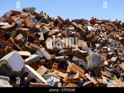 Messy pile of jagged red bricks and debris against blue sky. Stock Photo
