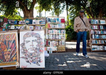 Havana, Cuba. 28th Jan, 2015. A man smokes a cigar as he stands between bookshelves and a poster which depicts the likeness of Cuban revolutionary Ernesto 'Che' Guevara in the city centre of Havana, Cuba, 28 January 2015. Guevara was born in Argentina and had joined Fidel Castro from 1956 to 1959 as one of the leaders of the Cuban revolution. Photo: Lisette Poole/dpa/Alamy Live News Stock Photo