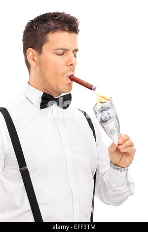 Vertical shot of a rich man lighting up a cigar with burning dollar isolated on white background Stock Photo