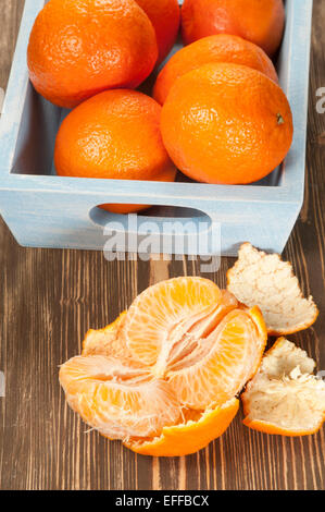 Tangerine fruits in a timber box on a wooden table Stock Photo