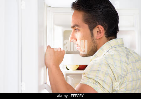 young handsome man looking for food in the fridge Stock Photo