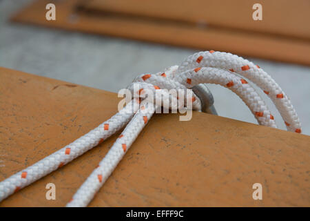 White boating knot rope tied around rusty pole by the water. Stock Photo