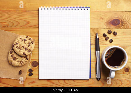 Cup of coffee with chocolate cookies and opened notepad on desk. Top view Stock Photo