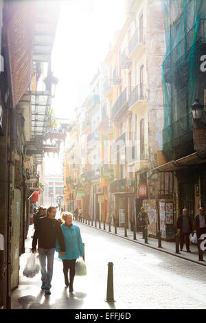 Shoppers in a narrow Valencian city street with Sun streaming Stock Photo