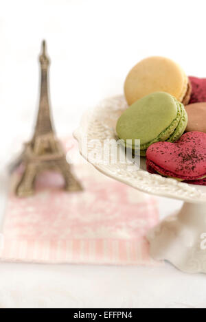 White pedestal plate with multi colored macaroons and a small Eiffel Tower in background Stock Photo