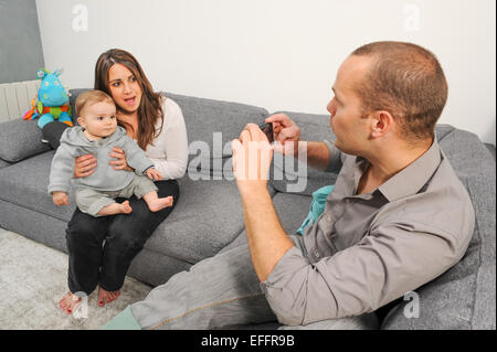 Father taking picture of mother and son at home Stock Photo
