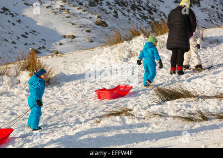 A family sledging on Kirkstone Pass in the Lake District, UK. Stock Photo