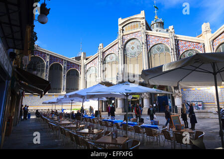 A street cafe awaiting customers in front of the south facade and entrance to Valencia Central Market Stock Photo