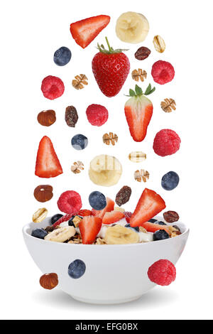Falling ingredients of fruit muesli for breakfast in bowl with fruits like raspberry, blueberries, banana and strawberry Stock Photo