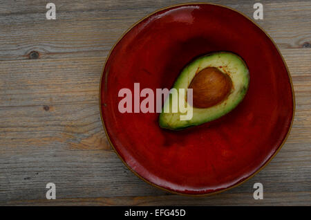 avocado half on a red ceramic bowl Stock Photo