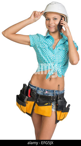 Woman in hard hat and tool belt calling on mobile phone Stock Photo