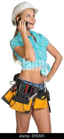 Woman in hard hat and tool belt calling on mobile phone Stock Photo