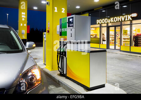 Car in gas station. Fuel, petrol dispenser, pump, handles and pillars. Fueling. Estonia. Lighted window of convenience store. Stock Photo