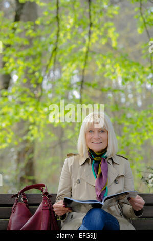 Senior woman reading a blue book outdoors Stock Photo - Alamy