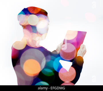 Woman with digital tablet composited with images of lights Stock Photo