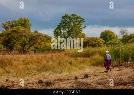 Man in traditional clothing wlks on dry landscape. Stock Photo