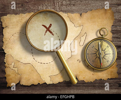 aged antique nautical compass and magnifying glass on table with treasure map Stock Photo