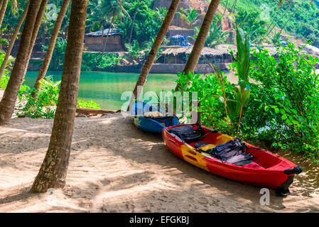 two canoes in the shade of tropical palm trees on the beach Stock Photo