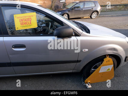 Manchester UK  04th February 2015 A car is clamped on Eversley Road, Didsbury, South Manchester for being untaxed, but a valid tax disc is in the window. Unfortunately  for the owner, it should be on the passenger side. At the time of the offence tax discs are no longer issued. Taxed Car Clamped  Manchester, UK Credit:  John Fryer/Alamy Live News Stock Photo