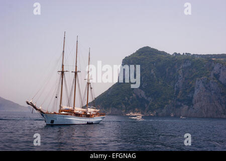 Sail frigate anchored at the coast of Capri, Italy. In the background is Mount Tiberius. Stock Photo