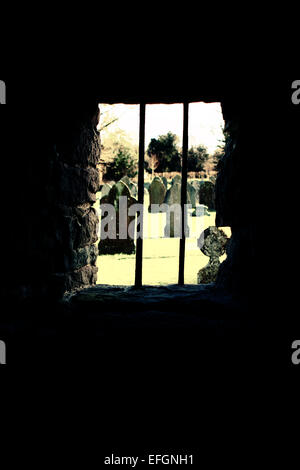 View from behind bars in a old medieval tower overlooking a graveyard Stock Photo