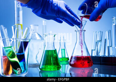 Laboratory equipment, lots of glass filled with colorful liquids, hand poured Stock Photo
