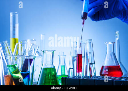 Laboratory equipment, lots of glass filled with colorful liquids and hand injection Stock Photo