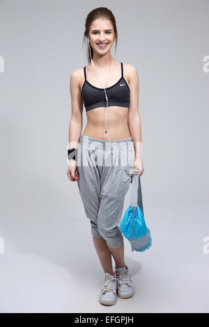 Full length portrait of a happy sporty woman standing with yoga mat Stock Photo