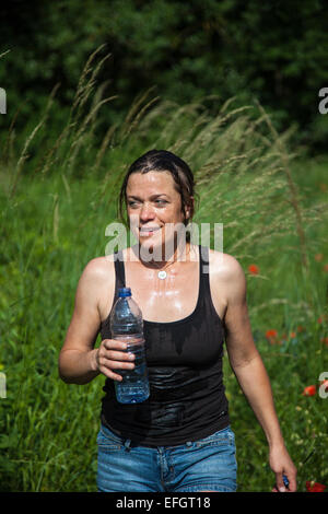 Young woman with water bottle out walking in a field Stock Photo
