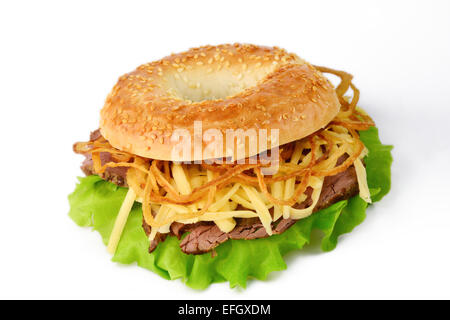 Studio isolated: fresh sesame bagel with lettuce, roasted beef, grated cheddar cheese and onion rings Stock Photo