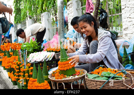 Lao young lady selling special arranged flowers for Lao New Year (Pii Mai) celebration in Luang Prabang. Stock Photo