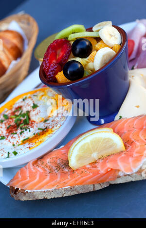 Salmon, fried eggs, cheese, ham and fruit salad on a plate Stock Photo