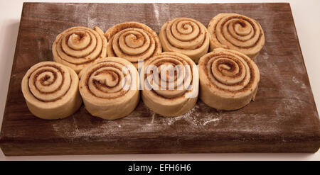 Uncooked cinnamon rolls on a wooden cutting board. Stock Photo