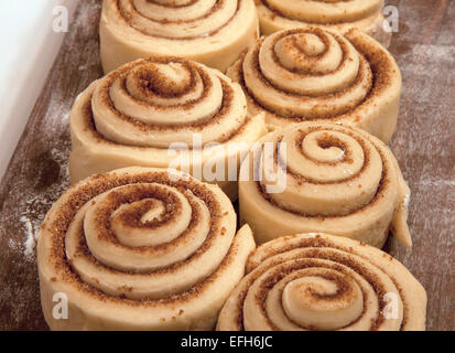 Uncooked cinnamon rolls on a wooden cutting board. Stock Photo