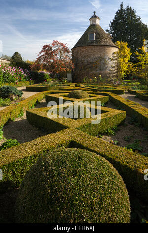 The geometric shape of the box hedge parterre and c.1685 dovecote in the walled garden of Rousham House, Oxfordshire, England Stock Photo