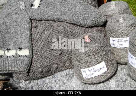 Grey sheep wool yarn bobbins and knitwear on agricultural show market stall Stock Photo