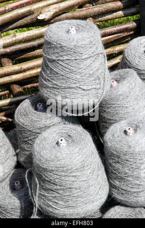 Grey sheep wool yarn bobbins in basket on agricultural show market stall Stock Photo