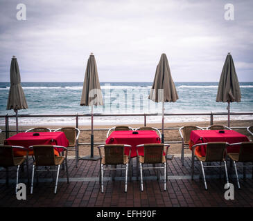 Empty tables and chairs outside restaurant overlooking beach. Stock Photo