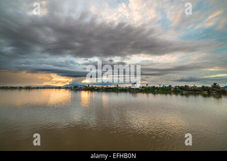 Cloudscape at sunset on the Sarawak River from the Waterfront Promenade in Kuching, Borneo, Malaysia. View of a stilt village. Stock Photo