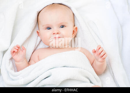 Cute smiling baby girl lying on white towel