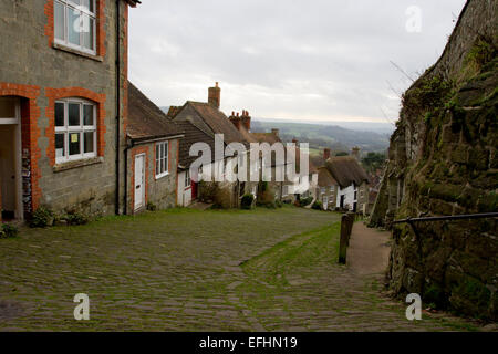 View at the top of Gold Hill, famous cobbled street in Shaftesbury, Dorset, England, looking downhill and to countryside beyond. Stock Photo