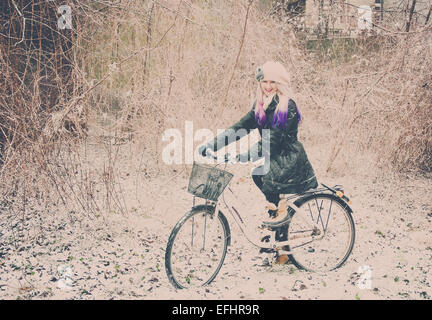 A blond girl riding her bike with a basket through the snow in Copenhagen Denmark. Stock Photo