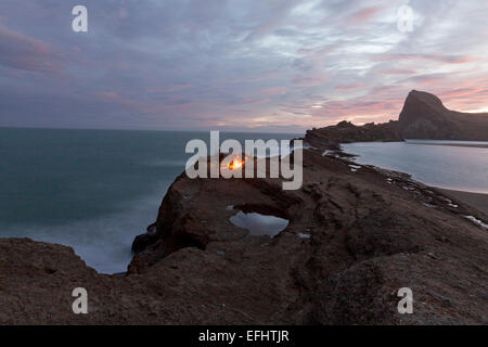 Anglers fishing at night from a cliff, campfire, Castle Rock, North Island, New Zealand Stock Photo