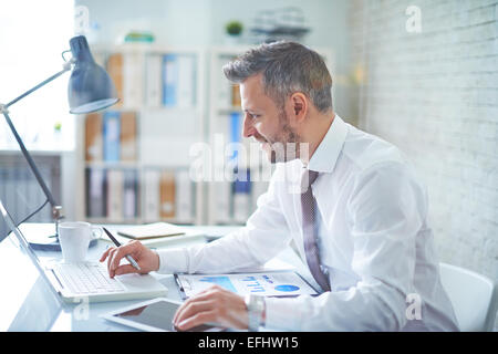 Elegant businessman analyzing data in office Stock Photo