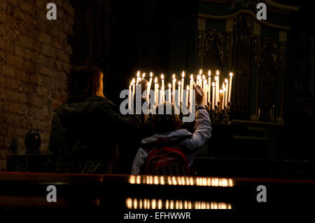 Mother and son lighting candles in a church in Venice, Italy Stock Photo
