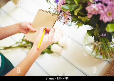 Young female making notes in notepad by workplace Stock Photo