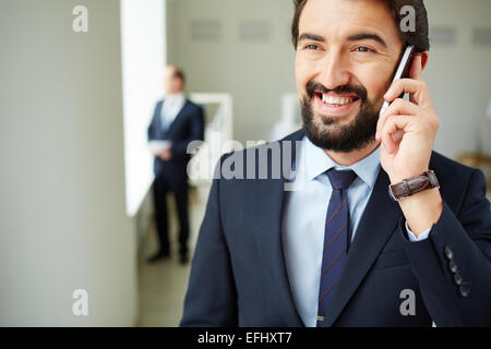 Young businessman speaking on the phone on background of his colleague in office Stock Photo