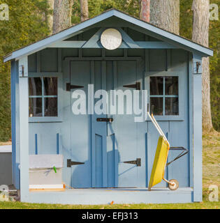 Blue garden shed with yellow wheelbarrow on porch Stock Photo