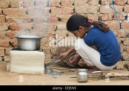 India, Uttar Pradesh, Agra, Indian girl tending to outdoor fire using buffalo dung as fuel. Stock Photo